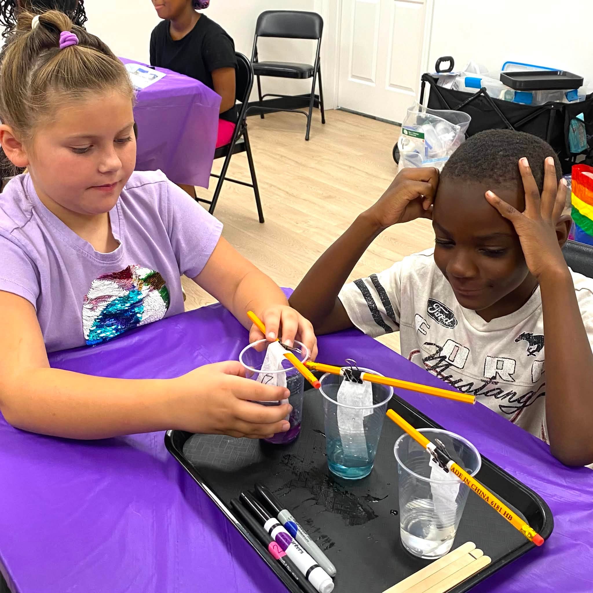 A girl and a boy doing a science experiment using liquid and test strips.